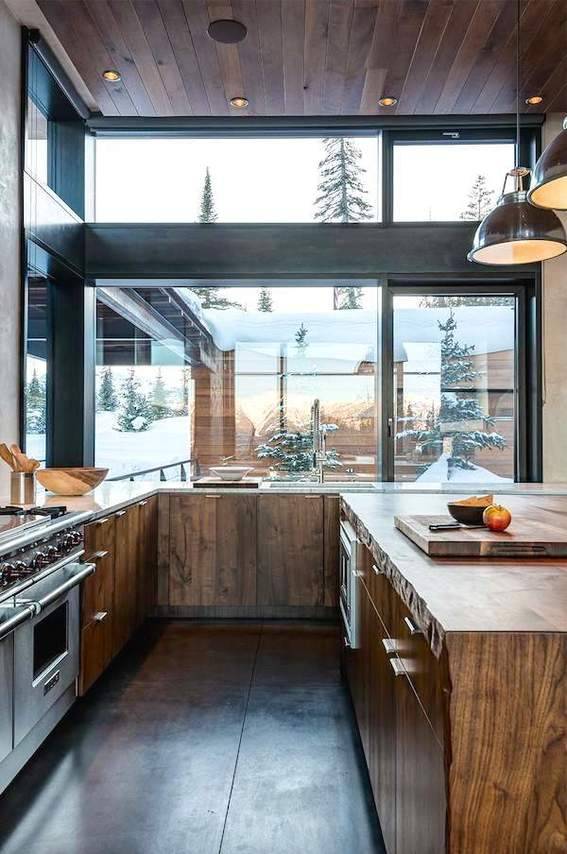 Windows surround the wooden counters in a kitchen that also has a wooden ceiling.