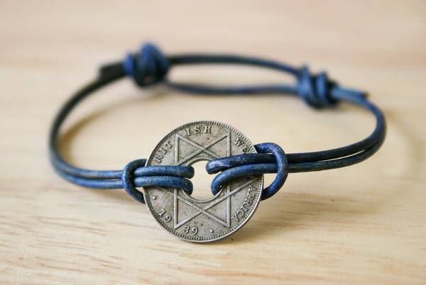 A bracelet is made with blue string and a silver decorative coin.