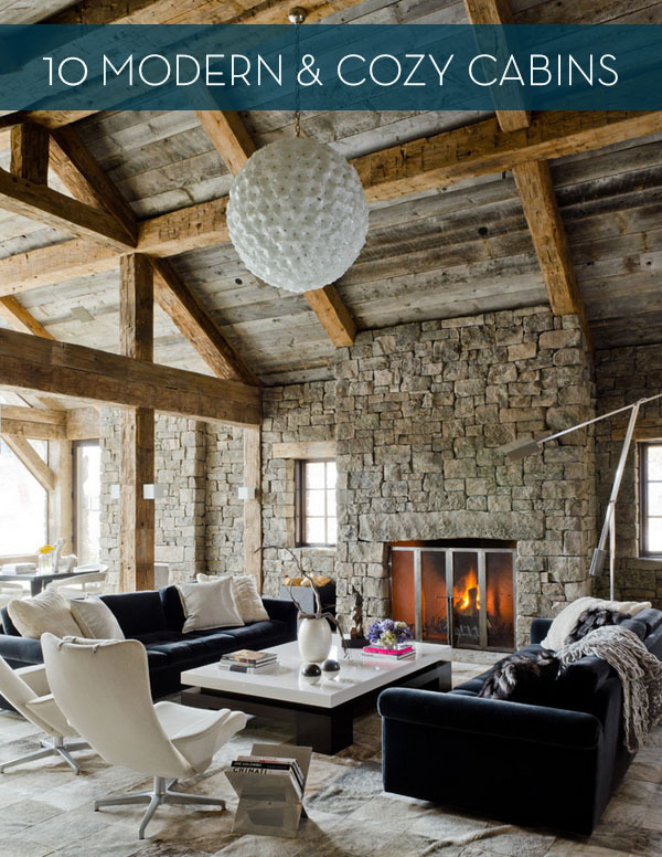 The interior of a stone cabin with with a high wooden ceiling and a large white globe pendant light, a fireplace and two black sofas.