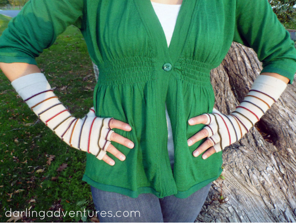 A woman in a green top and long fingerless gloves has her hands on her hips.
