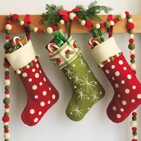 Red and green Christmas stockings hang with candy and goodies in them.