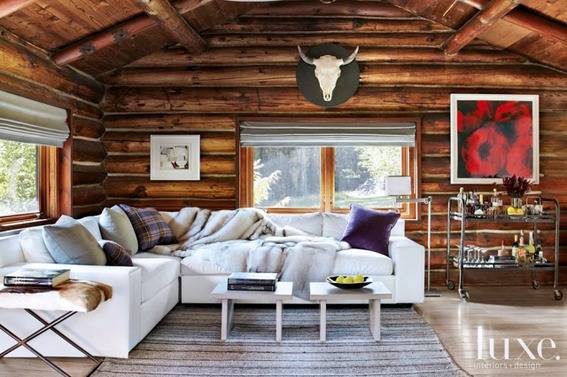 White furniture fills a room in a log cabin with a cow skull and other art work on the all.