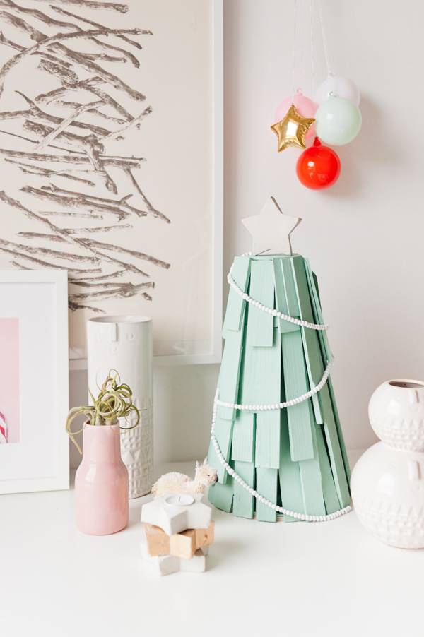 Wood shims shaped into Christmas tree shape with light green paint and ornaments.
