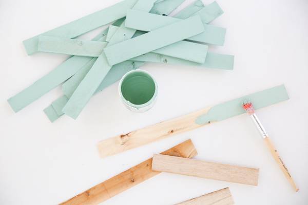 Light blue colored paint bottle, colored and uncolored wood sticks and paint brush.