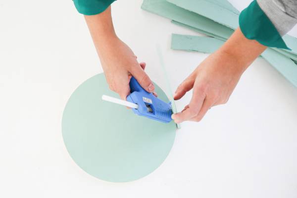 Man is gluing circle shaped colored wood with rectangular colored wood.