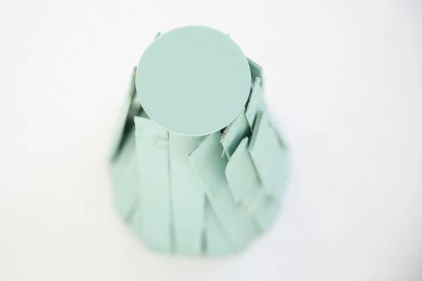 Tabletop Christmas tree stand made from small pieces of wood painted green.