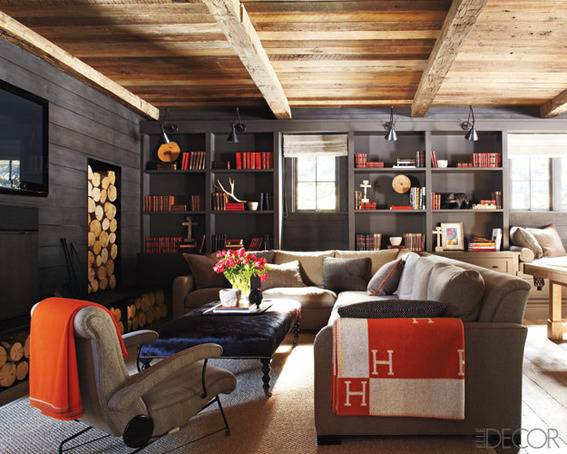 Black shelves sit against the wall in a room with seating furniture and a wooden ceiling.