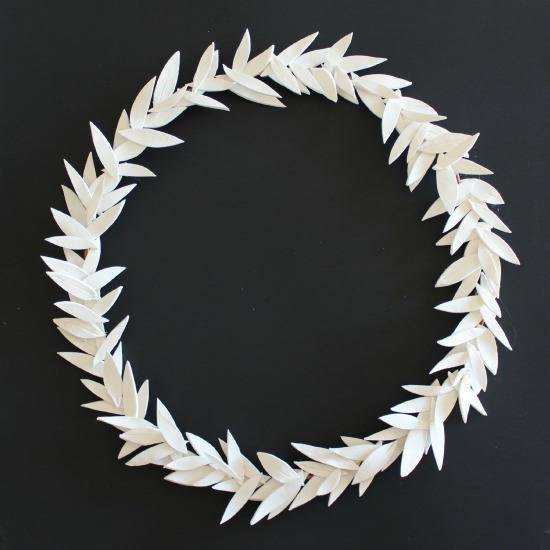 A white wreath sits against a grey surface.