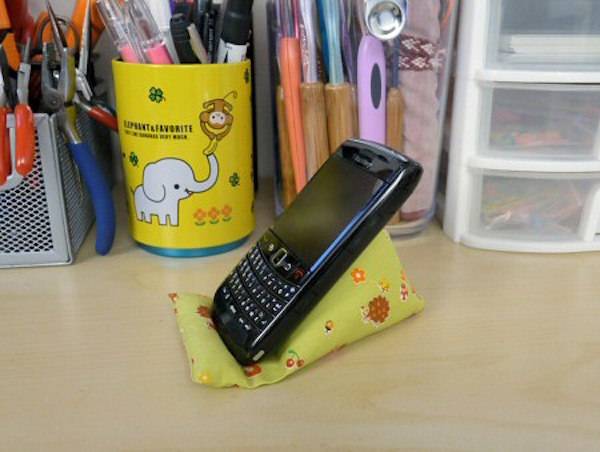 A blackberry phone sitting on a green cloth in front of a yellow cup with a white elephant on it.