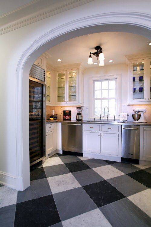 A black and white floor is in a kitchen.