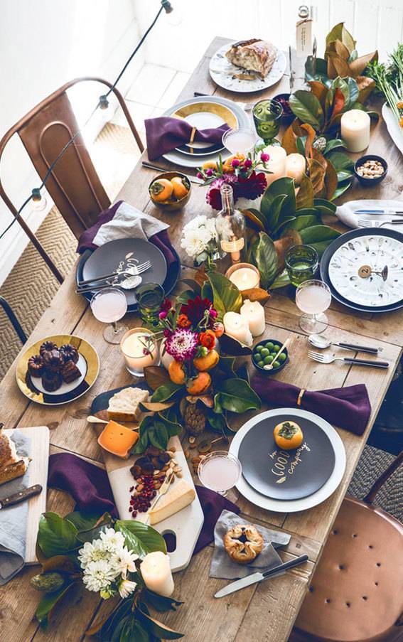 Food and decorations are set up at a long wooden table near natural lighting.