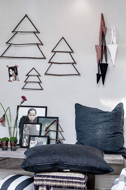 Christmas tree designs hang on the wall in a living room area.