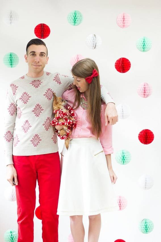 A couple holding a baby stand in front of a colorful background.