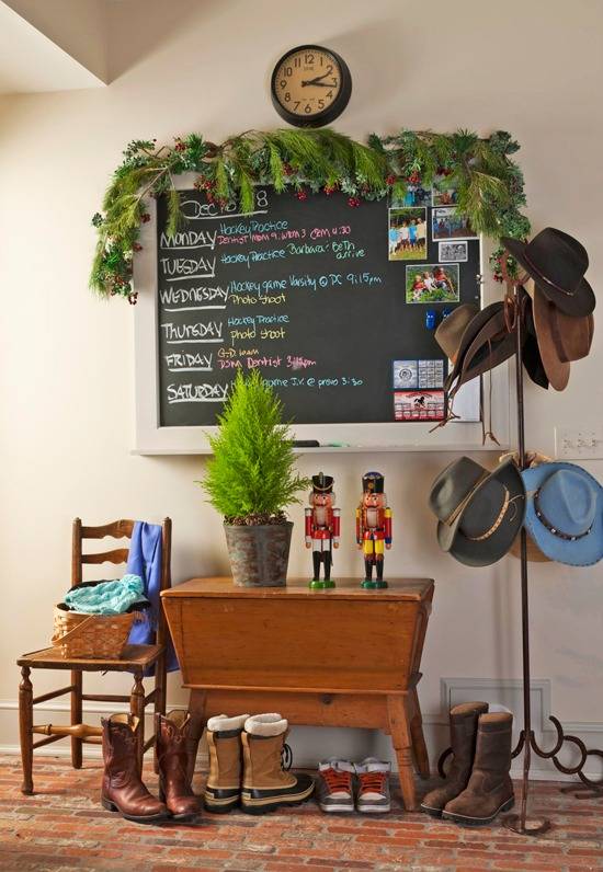 Shoes are lined up near a small table under a chalkboard near a wall.