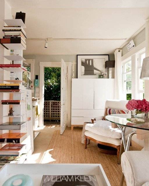 Shelves and living room furniture fill a room with wooden flooring.