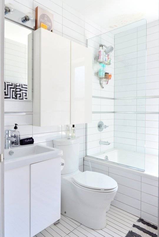 A white tiled bathroom with tub, sink and toilet.
