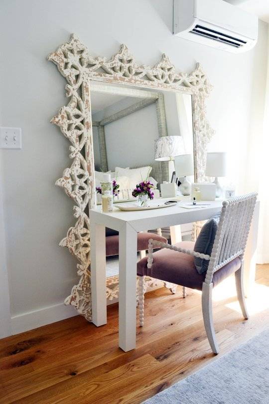 An ornate mirror with table and chair.