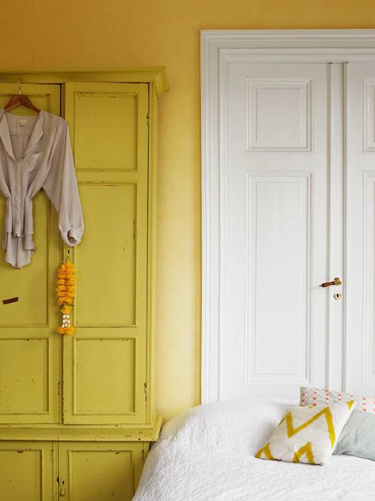 A yellow bedroom with a white bed and a white door.