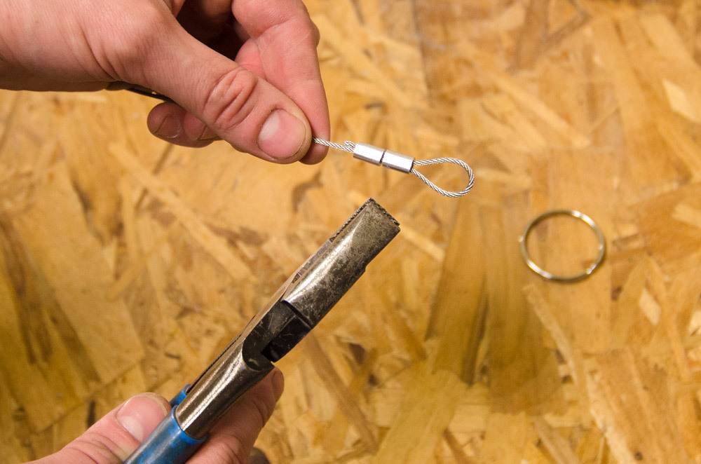 A tool is being used on a wire in a person's hand.