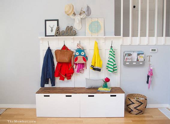 White mudroom storage display with hooks for coats and drawers for storage.