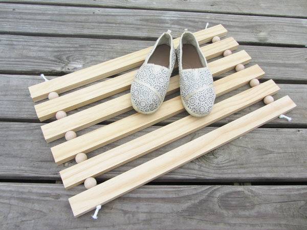 Pair of shoe is placed on the wooden doormat.