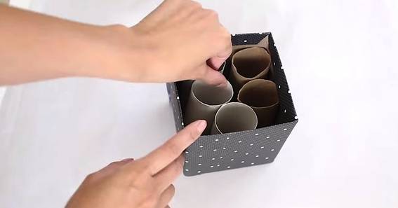 A person arranging empty paper rolls inside the paper box.