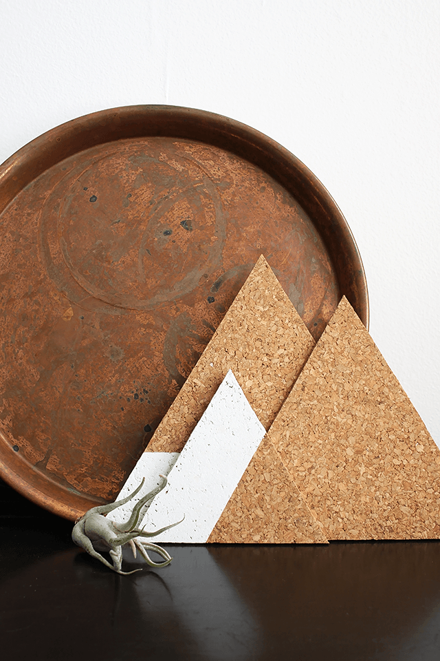 A brown metal plate standing on a table near three cardboard triangles.