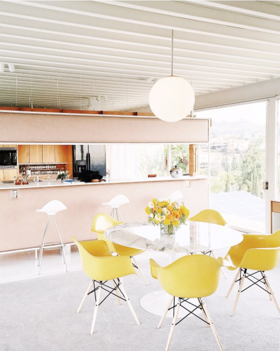 The kitchen during the daytime with yellow chairs, and large windows.