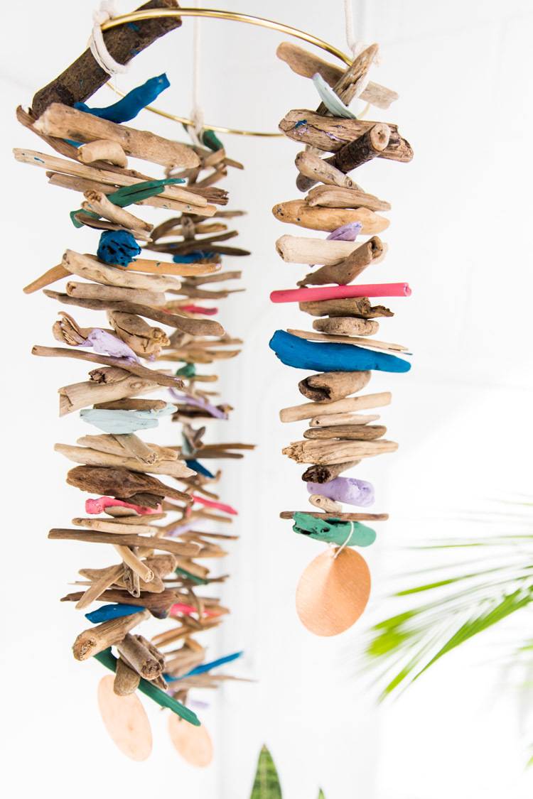 Two hanging pieces of string with different size tiny sticks stacked among colored pieces of wood.
