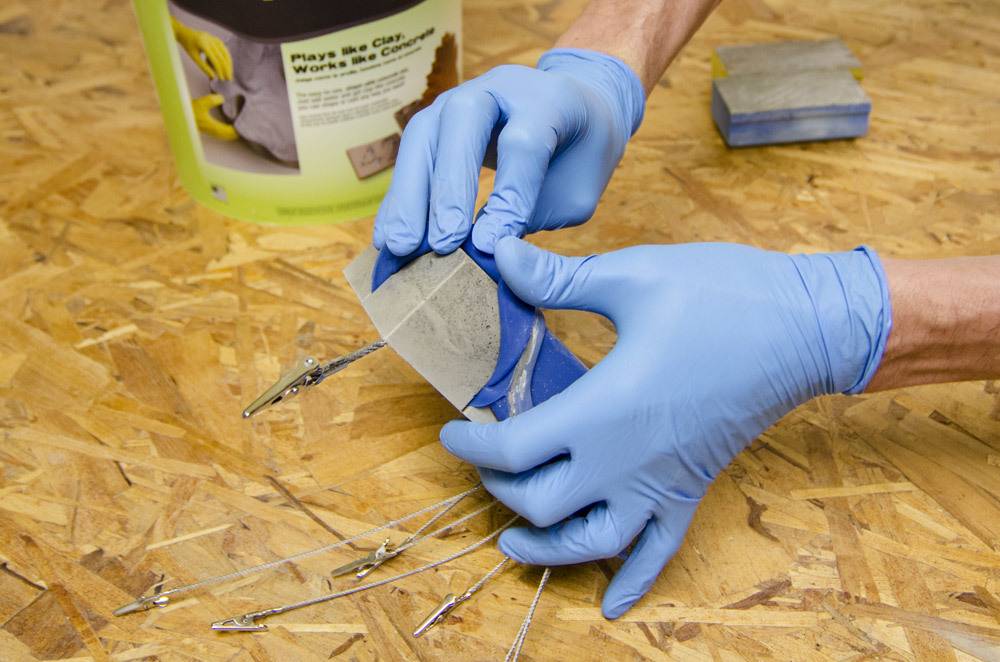 A person with blue gloves preparing concrete cubes.