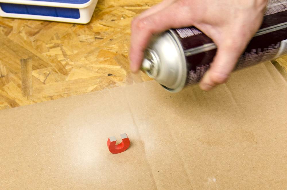 Man spraying color to u shaped red color piece.