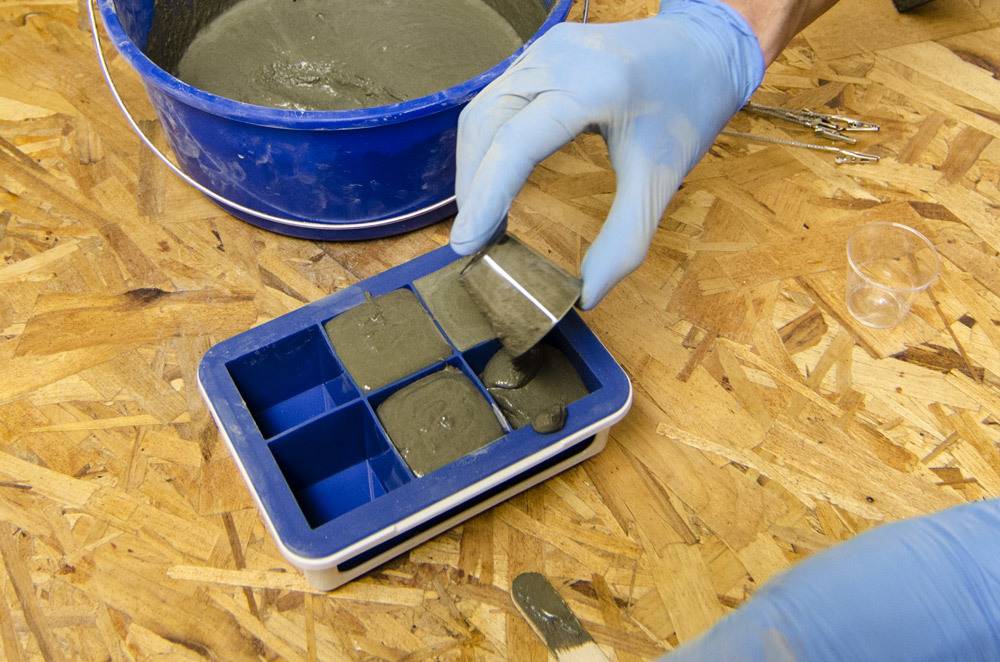A person pouring cement into a blue mold.
