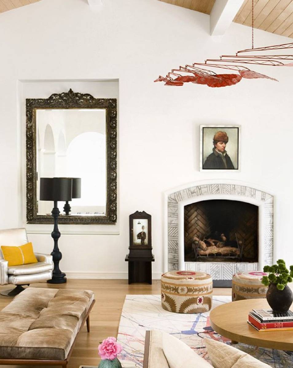A painting is hanging over a fireplace in a white room with a slanted roof.