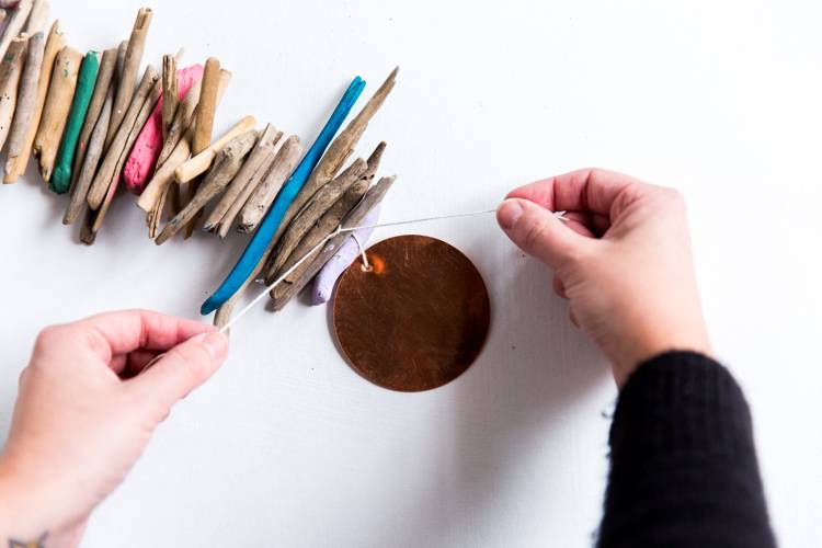 A person does crafts with small brown wooden sticks and paint.