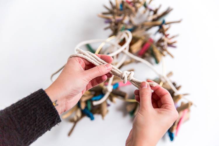 A person uses two hands to make a craft with some string.