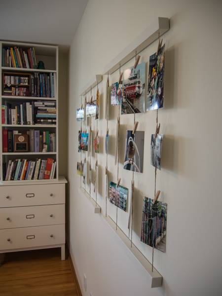 Several pictures hang from a wall next to a bookshelf.
