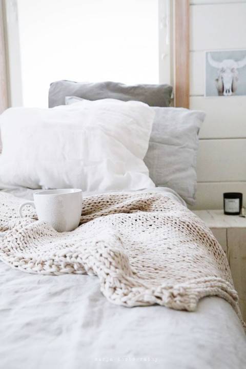 A bed with a coffee cup on it.