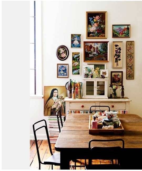 Many pictures are on the wall behind a table.