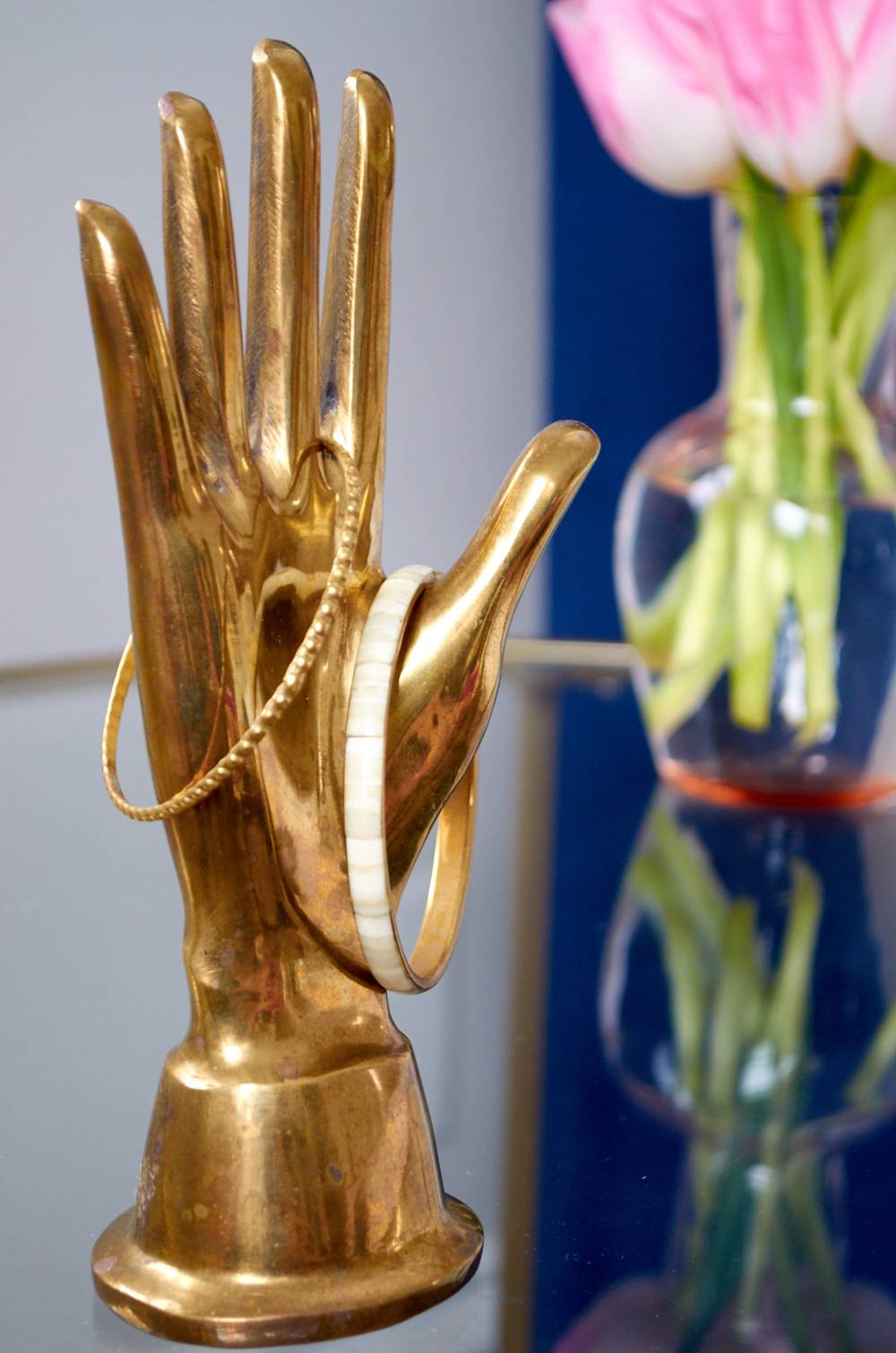 A gold hand statue holds two bracelets.