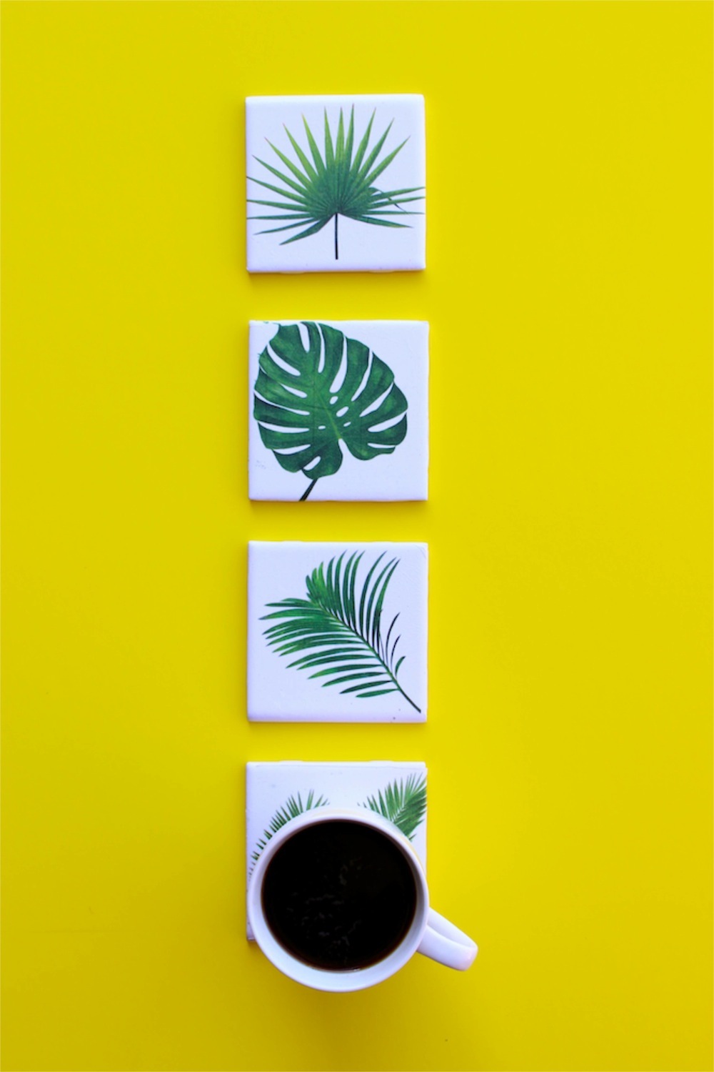 tropical leaf coasters and a cup of coffee with a yellow background