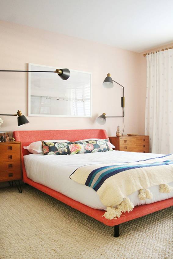 A made bed with a blue striped throw blanket on an orange bed fram with four spotlights above it.