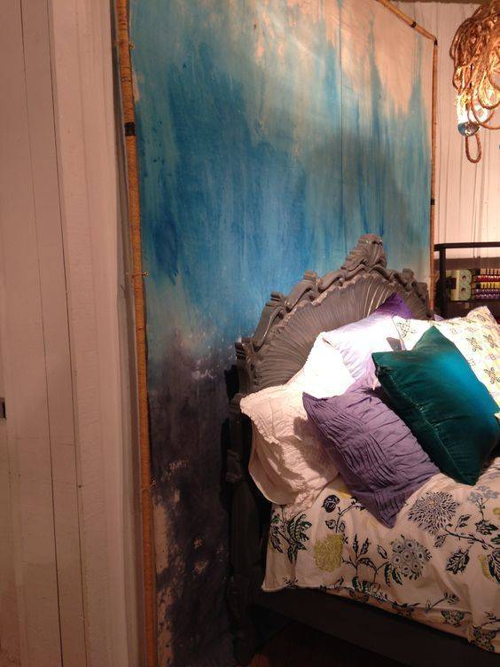Blue colored canvas drop cloth wall art behind the wooden bed.