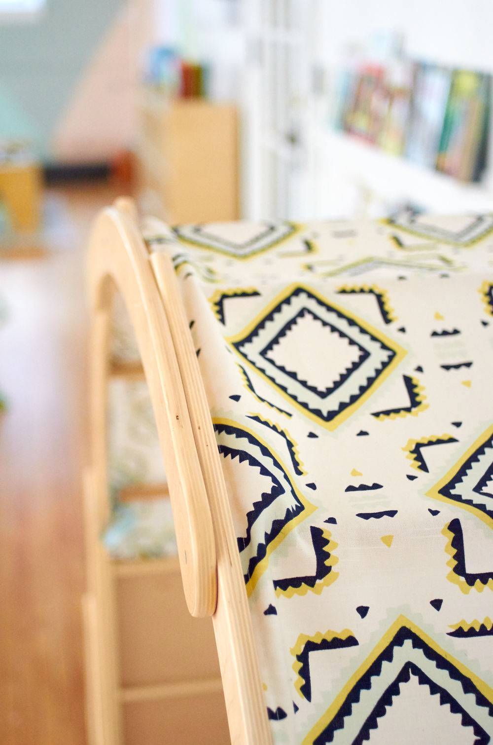 Geometric print on beige fabric hangs over a natural wood frame.