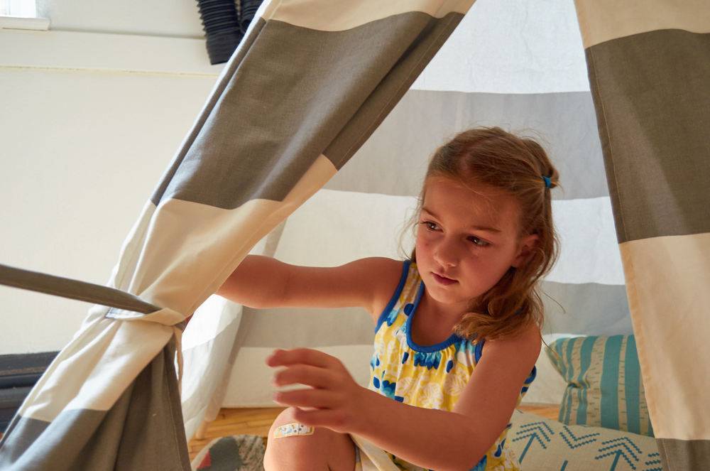 A little girl plays in a tent.