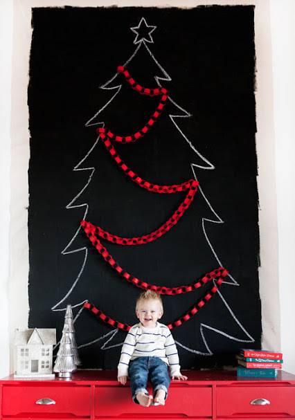 Black drop cloth wall art that looks like a Christmas tree with red decorations on it.