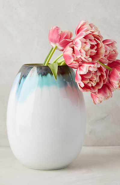 Lots of flowers in a white tulip shaped flower vase.