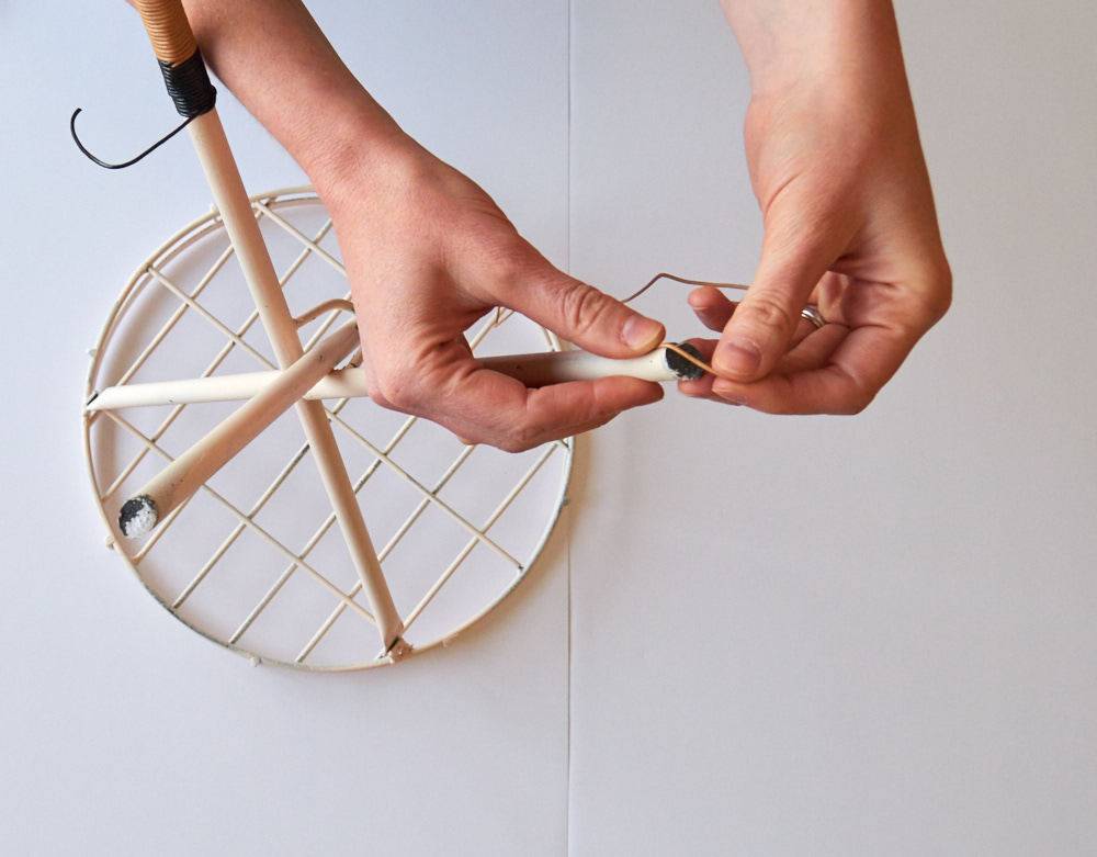 A person weaves things with a circular crafting thing.