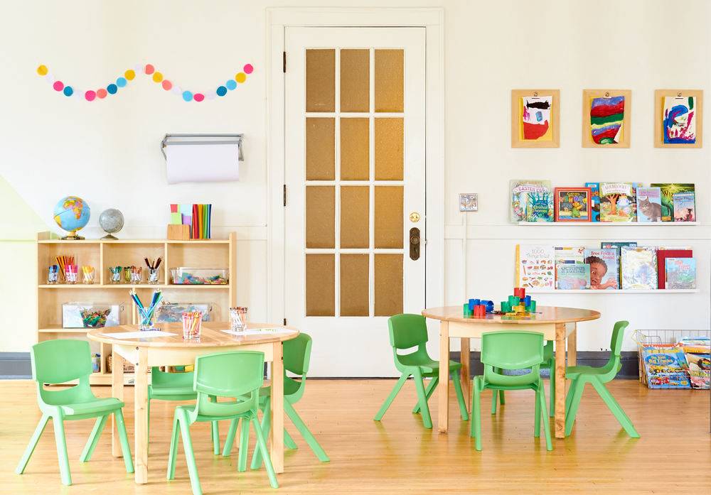 A nursery school room with tables and artwork.