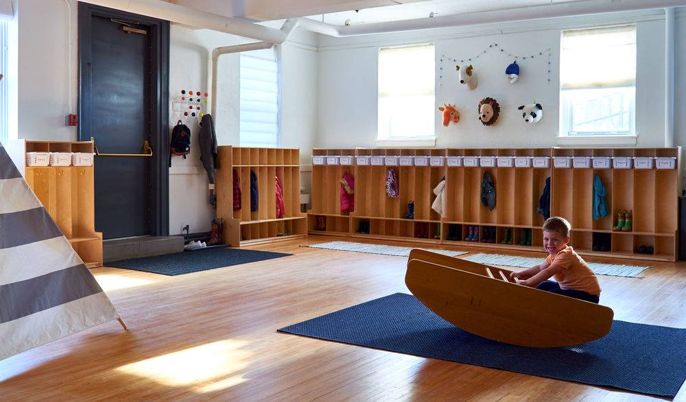 One child is playing on a wooden swing in a wooden gym room.
