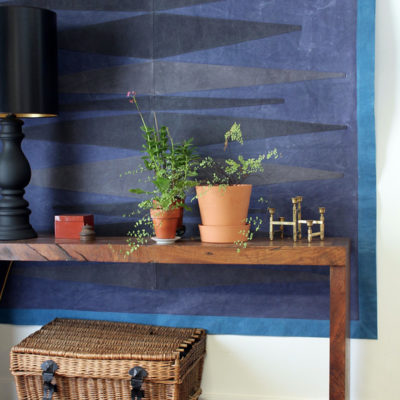Two flower pots on a wooden surface against a blue wall